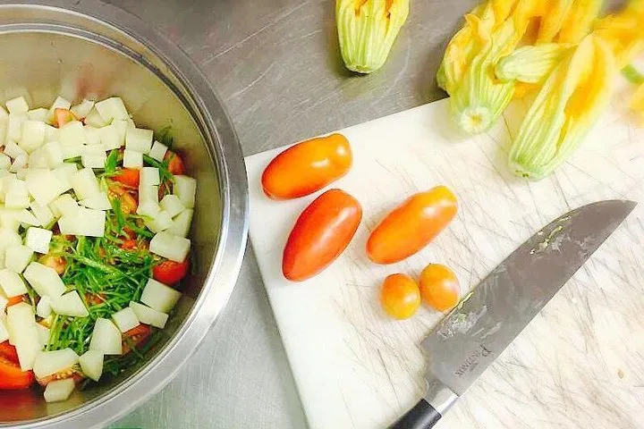 Zucchiniblüten, geschnittenes Gemüse und Tomaten auf einem Schneidebrett